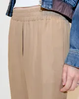 Pantalón babucha negro de tiro medio confeccionado en tela italiana. Presenta cintura elastizada, bolsillos laterales funcionales y piernas tipo pitillo con raya de aplomo.