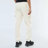 Pantalón de jogging color blanco hueso, de corte holgado, con cintura elástica ajustable con cordón, bolsillos laterales y bolsillos tipo cargo con solapa en los muslos.