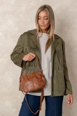 Cartera de mano con acabado envejecido y brillante, diseño de cuerpo suave con fruncido en la parte superior. Incluye correa larga ajustable y herrajes metálicos oscuros.