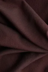 Top entallado de punto de crepé color marrón, con hombros descubiertos, escote ancho con doblez y detalle girado en el frente. Presenta frunces laterales para un efecto drapeado.