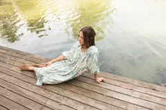Vestido midi de corte camisero con estampado floral en tonos verde agua y crema. Presenta cuello a la base, cierre frontal con botones y mangas al codo con terminación elástica.