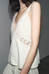 Top blanco de escote pico y tirantes finos, con detalle de encaje a tono y bajo recto.