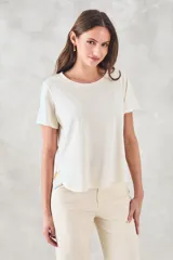 Remera de algodón peinado color crudo, con cuello redondo, mangas cortas y corte distendido. Presenta detalles de vainillas laterales y ruedo curvo.