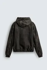 Cazadora de denim negro con efecto lavado, corte relajado, cierre frontal con cremallera, capucha ajustable y forro interior de borreguillo. Presenta bolsillos frontales tipo canguro y acabados elásticos en puños y ruedo.