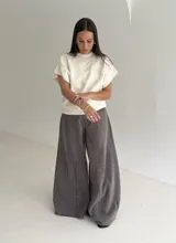 Chaleco tejido de punto color crudo, con cuello redondo y diseño de flor en relieve en el frente. Presenta un corte holgado y mangas cortas con terminación acanalada.