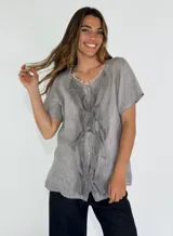 Camisa de lino y algodón color rosa claro, con cuello en V, mangas cortas y volados frontales.