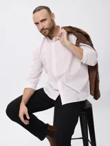 Camisa de manga larga con diseño de microcuadros, cuello clásico y cierre frontal de botones. Presenta un bordado sutil en la pechera y puños abotonados.