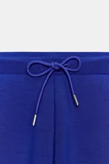 Pantalón flare de tiro medio, color azul, confeccionado en tejido de punto elástico. Cuenta con cintura elástica ajustable con cordón, bolsillos delanteros y corte amplio en las piernas.