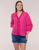 Blusa fucsia de tejido bambula, con escote en V y pechera decorada con encaje floral y botones forrados a juego. Tiene mangas 3/4 abullonadas con una franja intermedia de puntilla calada y puños elastizados.