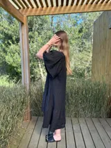 Vestido verde oliva de lino, corte suelto, con mangas abullonadas y volado en el ruedo.