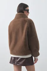 Tapado corto de textura tipo piel sintética en color marrón, con cuello redondo y cierre frontal de botones. Presenta un diseño de corte recto y holgado.