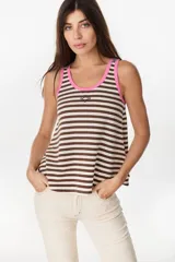 Musculosa de corte holgado con diseño a rayas horizontales en tonos marrón y crudo. Presenta ribetes en color fucsia en el cuello redondo y en las sisas, además de un pequeño bordado decorativo en el centro del pecho.
