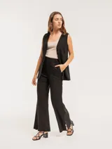 Pantalón negro de lino, tiro alto, corte palazo, con elástico en la pretina trasera, cierre delantero y broche interno. Tiene bolsillos laterales, dobladillo invisible y tajos a los costados.