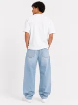 Jean de denim celeste claro, corte oversize tipo barrel con silueta curva y amplia caída hacia los tobillos, con diseño clásico de cinco bolsillos y trabillas para cinturón.