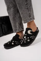 Suecos de cuero gamuzado color beige, con apliques metálicos y hebilla decorativa.