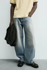 Jeans de hombre, corte balloon fit, tiro medio, confeccionados en denim rígido de algodón. Presentan un efecto lavado con un marcado degradado vertical, cinco bolsillos y cierre frontal con cremallera y botón.