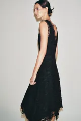 Vestido midi negro confeccionado en encaje de algodón, con escote en pico, diseño sin mangas, forro interior y bajo asimétrico.