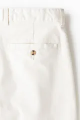 Pantalón de sarga de algodón con corte relajado, cierre de botón y cremallera, bolsillos laterales al bies y bolsillos traseros insertados con botón.