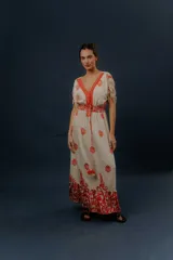 Vestido largo beige con estampado paisley en color azul marino, escote en V profundo con detalle bordado, mangas cortas amplias, cordón ajustable en la cintura con borlas y volados en el ruedo.