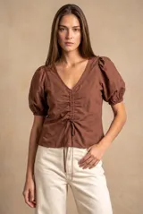 Blusa marrón de algodón con bordados sutiles, escote en V, mangas cortas abullonadas y detalle de fruncido con cordón ajustable en el centro del frente.