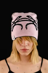 Beanie tejido reversible, con un lado negro y el otro lado rosado claro, ambos con diseño gráfico estampado en contraste.