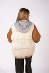 Campera puffer con diseño bicolor, cuerpo en color crudo y mangas en color marrón. Presenta cierre frontal con botones a presión, capucha integrada y puños de tejido acanalado a rayas. Incluye un parche bordado con las siglas NY en el pecho.