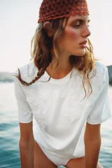 Remera blanca de manga corta y cuello redondo, de corte regular fit, con delicados detalles de bordados tonales en el frente.