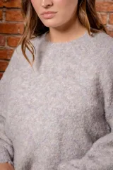 Sweater de tejido de punto con textura tipo mohair, color gris jaspeado con sutiles tonos pasteles, de corte holgado, cuello redondo y mangas largas con puños ajustados.