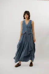Chaleco de denim azul con cuello en V, cierre frontal con botones metálicos y pespuntes en contraste.