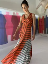 Vestido largo de lino rayado color naranja y marrón, con escote en V y espalda descubierta. La falda es amplia y con mucho movimiento.