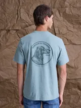 Remera de algodón color verde agua con estampa circular en la espalda que incluye la ilustración de un perro y la inscripción Benson & Thomas 1968.