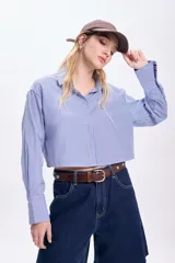 Camisa cropped de mangas largas con puños abotonados, de corte holgado y con estampado de rayas verticales azules y blancas.