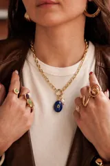 Collar de cadena de eslabones dorados con dijes colgantes, incluyendo una piedra ovalada azul y una perla de río.