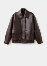 Chaqueta estilo bomber de cuero sintético en color marrón oscuro, con cuello camisero, cierre frontal de cremallera y botones a presión, bolsillos de parche con solapa y bajo elástico.