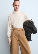 Pantalón tipo jeans de corte wide leg y tiro medio, confeccionado en denim de algodón color tostado. Presenta diseño de cinco bolsillos, cierre frontal con botón y cremallera, y costuras reforzadas.