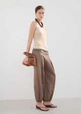 Chaleco de punto grueso color beige, con diseño recto, escote en V con solapa, sin mangas, tirantes anchos y cierre delantero con botones.