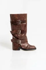 Botas de caña media en cuero color chocolate con acabado gastado. Presentan tres correas horizontales con hebillas metálicas ajustables y un diseño de solapas superpuestas. Cuentan con taco cuadrado bajo.