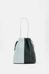 Bolso de hombro de piel con diseño bicolor en celeste y negro. Cuenta con cierre fruncido y pespuntes decorativos.
