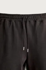 Bermuda estilo jogger de ajuste relajado, confeccionada en tejido interlock de algodón. Cuenta con cintura elástica ajustable con cordón, bolsillos frontales de vivo y diseño liso.