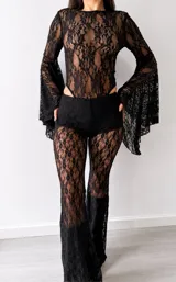 Body de encaje negro con diseño floral, cuello redondo y mangas largas acampanadas con terminación amplia.