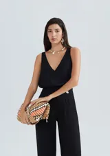 Blusa sin mangas de corte recto, con escote en V profundo y costura central vertical. Presenta un diseño minimalista y elegante.