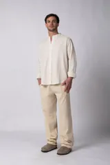 Camisa de manga larga confeccionada en lino, con cuello mao y cierre frontal de botones. Presenta un corte relajado y diseño minimalista.