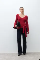 Sweater de punto acanalado color rojo, con escote en V, mangas largas acampanadas y lazo ajustable en la cintura.