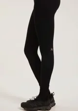 Calza deportiva de tiro alto confeccionada en tejido sin costuras, color negro, con ajuste ceñido al cuerpo y detalle de logo pequeño en tono contrastante sobre la pierna.