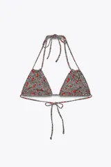 Top de bikini triangular con estampado animal print de leopardo y cerezas rojas. Tiene tirantes finos dobles y cierre ajustable con lazadas en cuello y espalda.