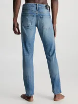 Pantalón de jean celeste de corte slim fit con efecto desgastado. El modelo presenta tiro bajo, pierna ajustada, bragueta con cremallera y diseño de cinco bolsillos.