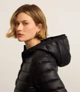 Campera puffer deportiva de mujer, confeccionada en tejido tecnológico ligero con relleno acolchado. Presenta capucha integrada, cierre frontal con cremallera y diseño de manga larga. La prenda destaca por su versatilidad, siendo capaz de transformarse en una pequeña cartera.