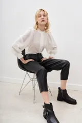 Pantalón estilo capri de efecto cuero negro, con corte holgado y detalles de costuras geométricas en la parte delantera.