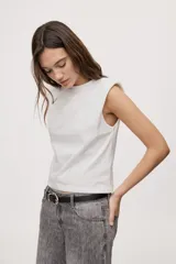 Remera sin mangas negra con cuello redondo y hombros estructurados con hombreras, de corte recto y largo a la cintura.