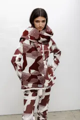 Bufanda de tejido de punto con diseño estampado geométrico en colores bordó y blanco, con etiqueta de marca visible en el extremo.